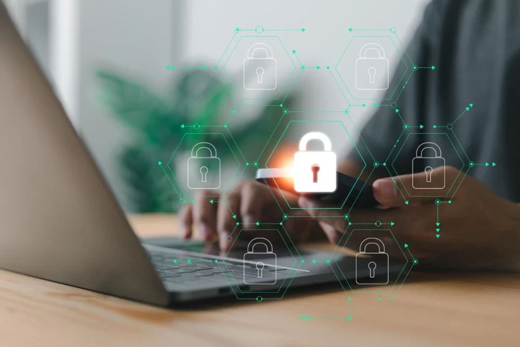A conceptual image of cybersecurity and data protection, showing a person using a laptop and a phone with a network of glowing lock icons. The central, highlighted lock on the phone emphasizes the importance of mobile security and PDPA compliance Malaysia.